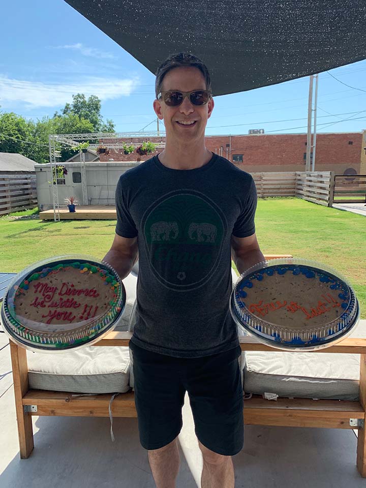 man smiling and holding two cookie cakes