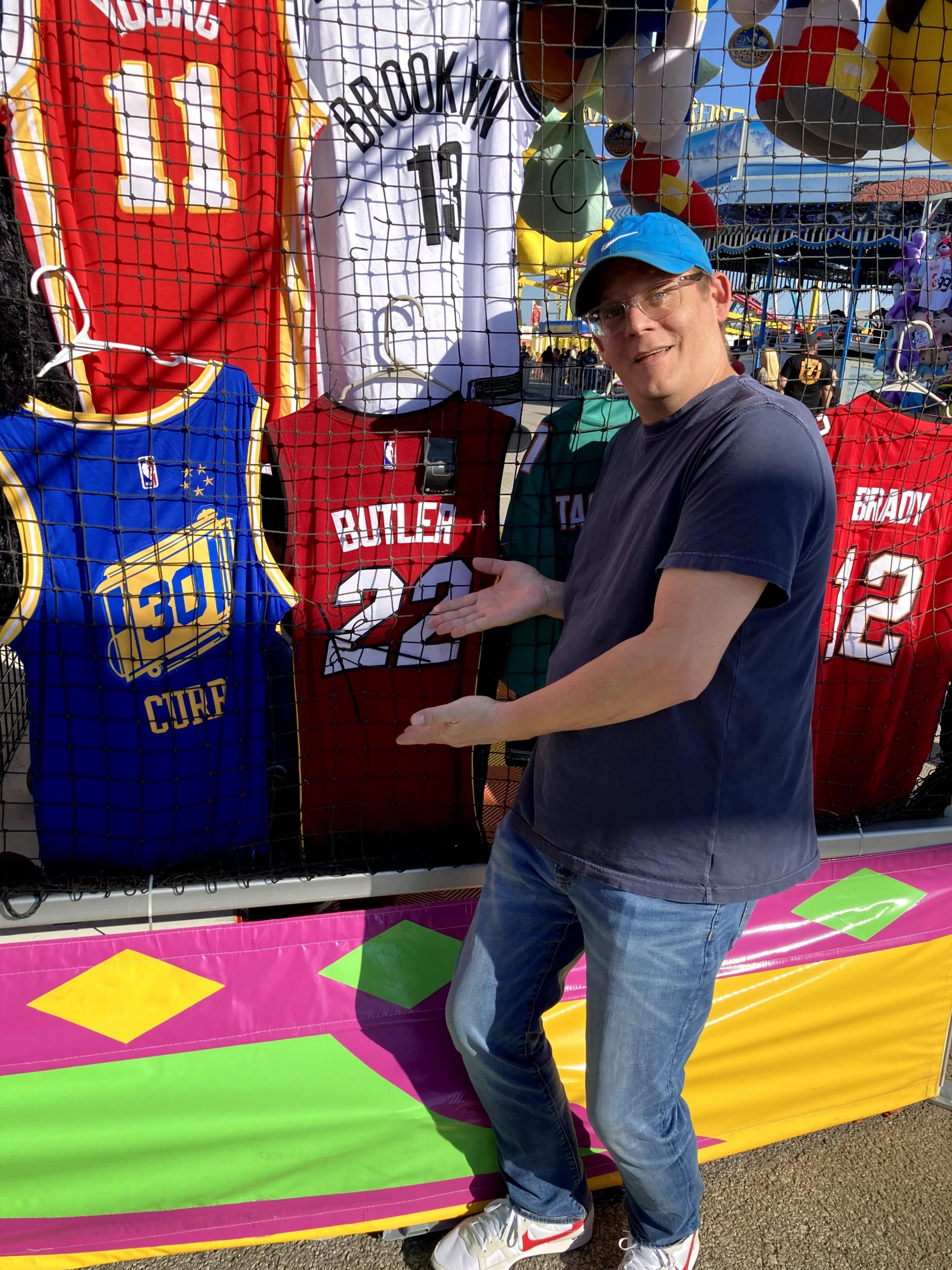 Man posing in front of sports team shirt selection.