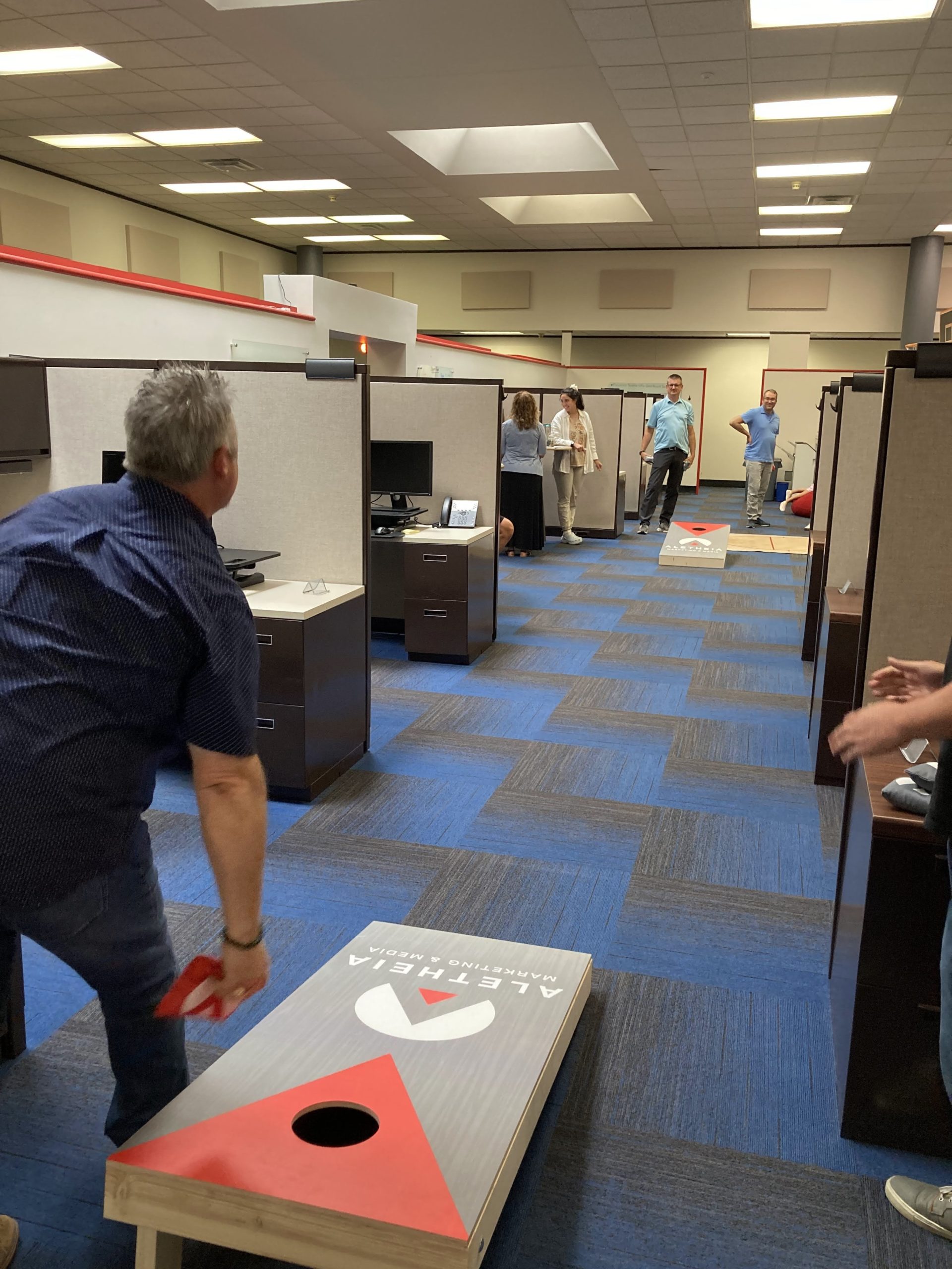 A group of people playing cornhole in the Aletheia office.