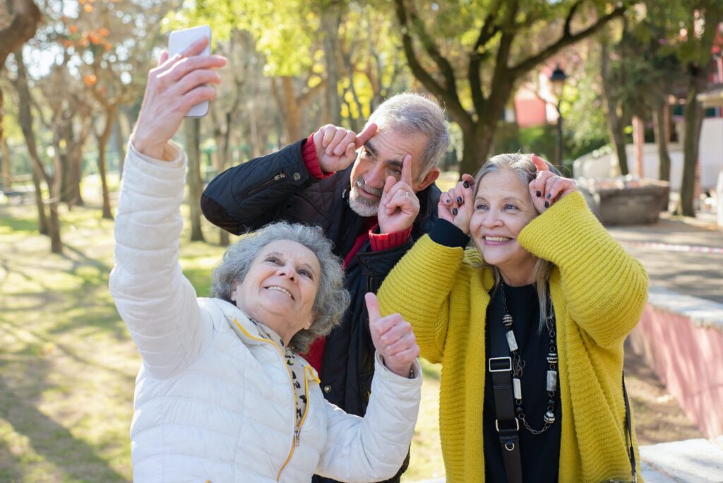group of seniors smiling while holding a camera and making silly faces